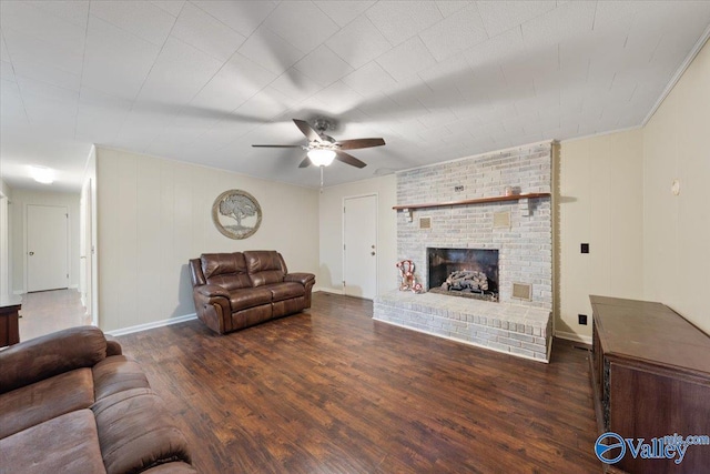 living room with a brick fireplace, dark wood-type flooring, and ceiling fan