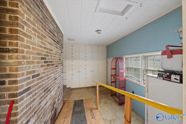 interior space with crown molding, vaulted ceiling, and brick wall