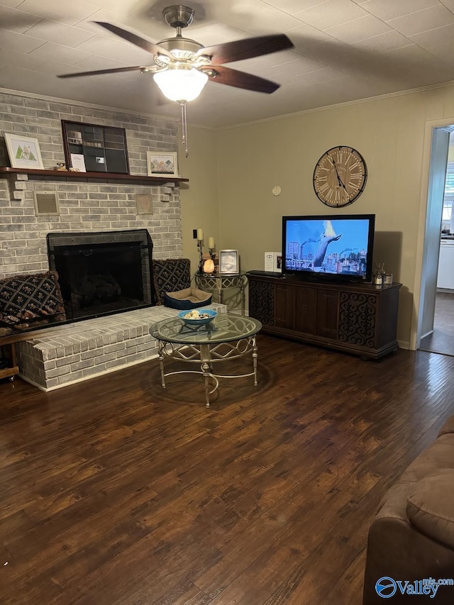 living room featuring wood-type flooring, crown molding, ceiling fan, and a fireplace