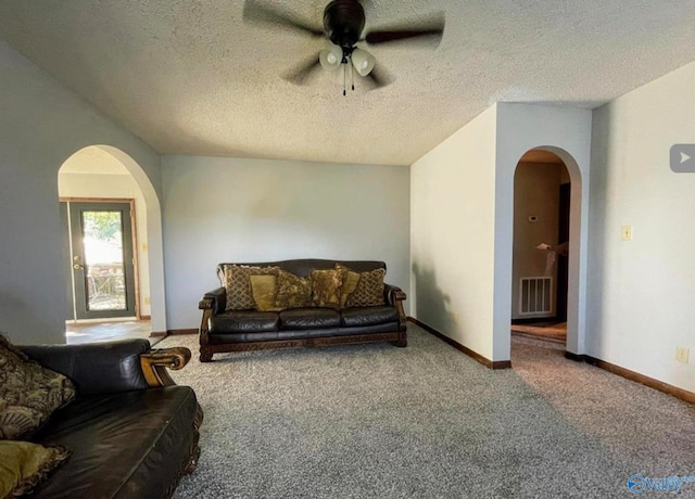 carpeted living room featuring ceiling fan and a textured ceiling