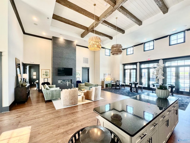 interior space featuring beamed ceiling, hanging light fixtures, hardwood / wood-style flooring, a large fireplace, and a towering ceiling