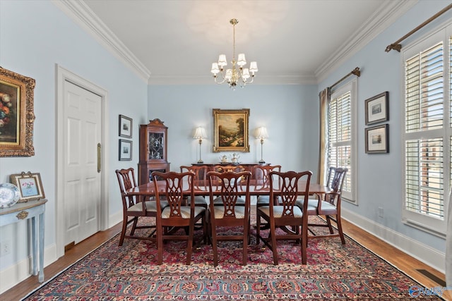 dining room with a notable chandelier, baseboards, wood finished floors, and crown molding