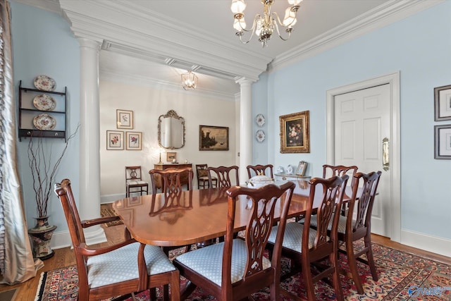 dining room featuring crown molding, a notable chandelier, decorative columns, and wood finished floors