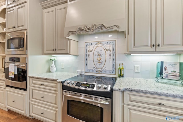 kitchen with custom range hood, appliances with stainless steel finishes, backsplash, and light stone countertops