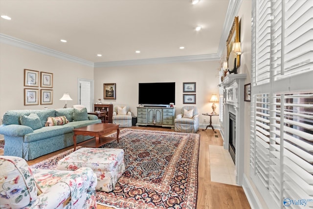 living room featuring baseboards, a fireplace with flush hearth, ornamental molding, light wood-style floors, and recessed lighting