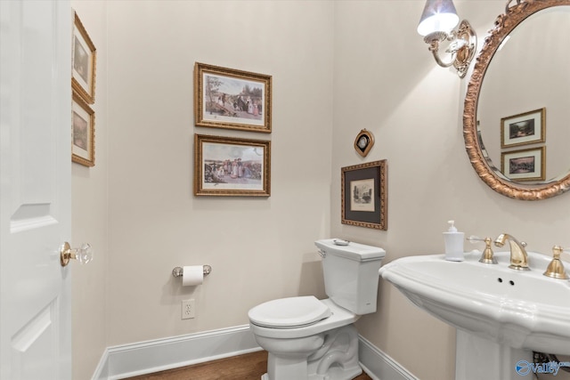 bathroom featuring baseboards, a sink, toilet, and wood finished floors