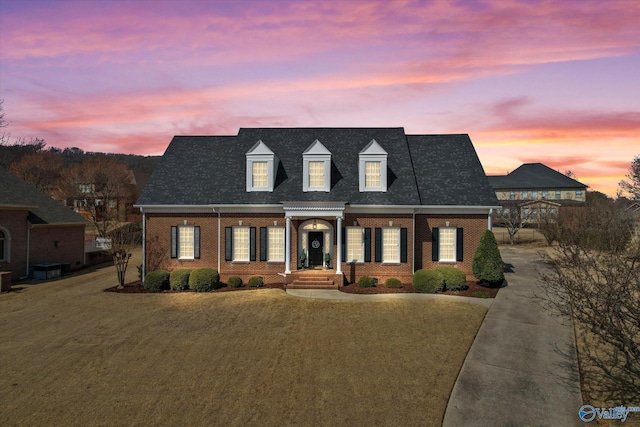 cape cod house featuring brick siding