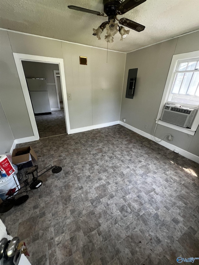 spare room with ceiling fan, cooling unit, a textured ceiling, baseboards, and electric panel