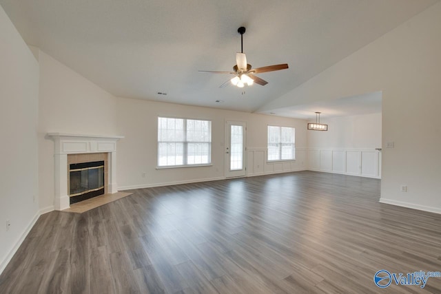 unfurnished living room featuring a ceiling fan, a tile fireplace, vaulted ceiling, and dark wood finished floors