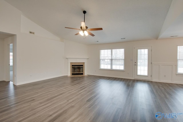 unfurnished living room with visible vents, a ceiling fan, wood finished floors, high vaulted ceiling, and a tile fireplace