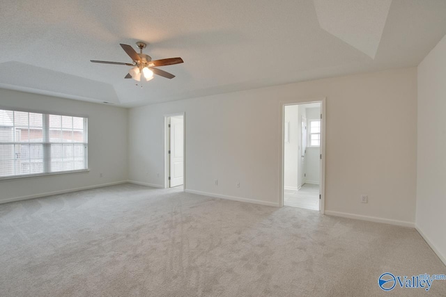 unfurnished room featuring a ceiling fan, light colored carpet, and baseboards