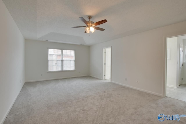 unfurnished room with a textured ceiling, baseboards, a ceiling fan, and light colored carpet