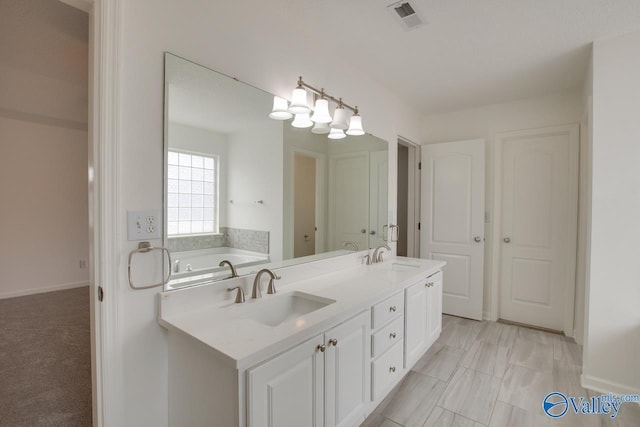 bathroom with visible vents, a sink, a garden tub, and double vanity