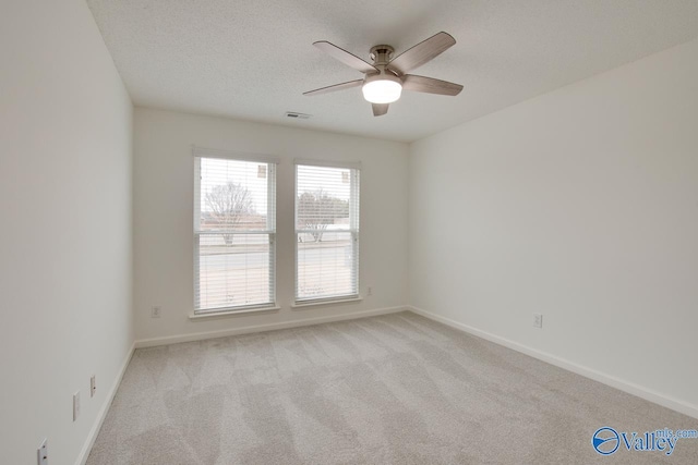 unfurnished room featuring visible vents, a ceiling fan, light carpet, a textured ceiling, and baseboards