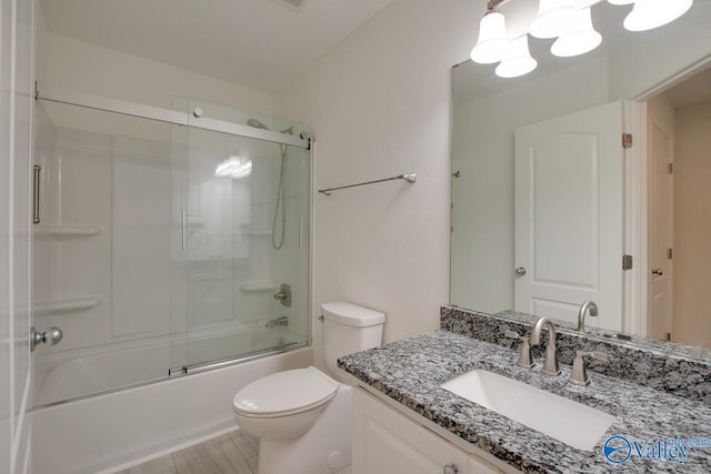 full bath with wood finished floors, combined bath / shower with glass door, vanity, and toilet