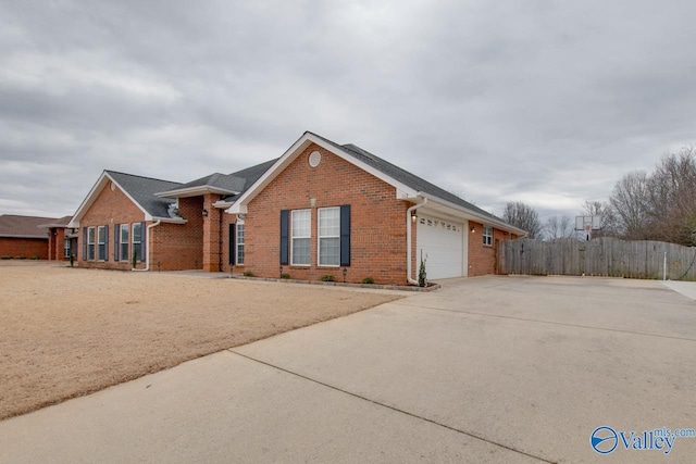 view of front of house featuring a garage, brick siding, driveway, and fence