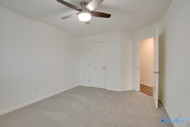 unfurnished bedroom featuring baseboards, a ceiling fan, and light colored carpet