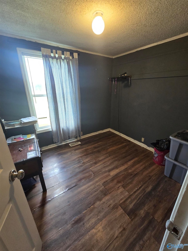 unfurnished bedroom with a textured ceiling, dark hardwood / wood-style floors, and crown molding