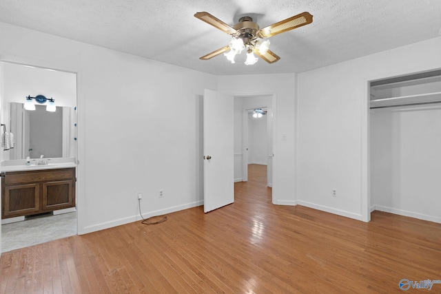 unfurnished bedroom with a closet, connected bathroom, light hardwood / wood-style flooring, and a textured ceiling