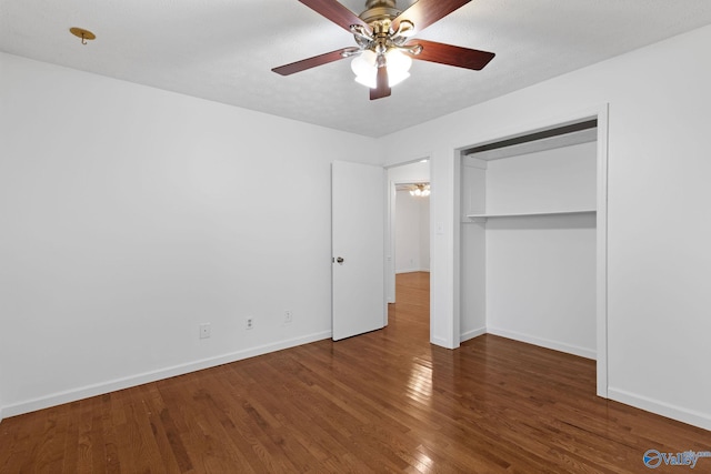 unfurnished bedroom with ceiling fan, dark hardwood / wood-style floors, a closet, and a textured ceiling