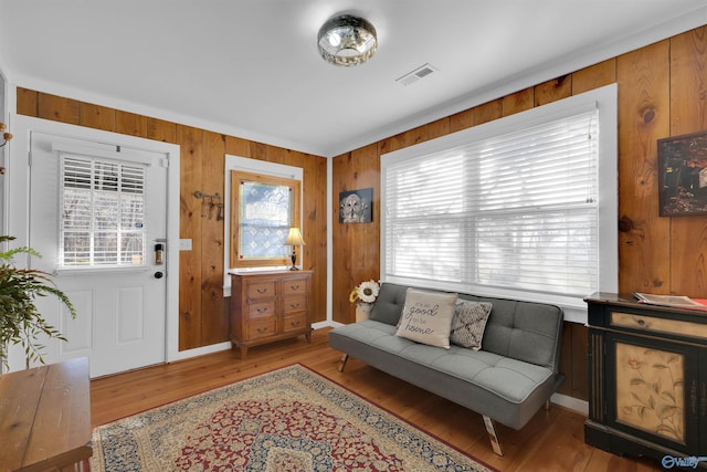 foyer entrance featuring visible vents, wood finished floors, and wood walls