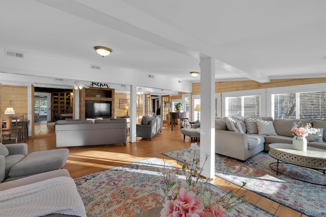 living area featuring visible vents, beam ceiling, and hardwood / wood-style flooring