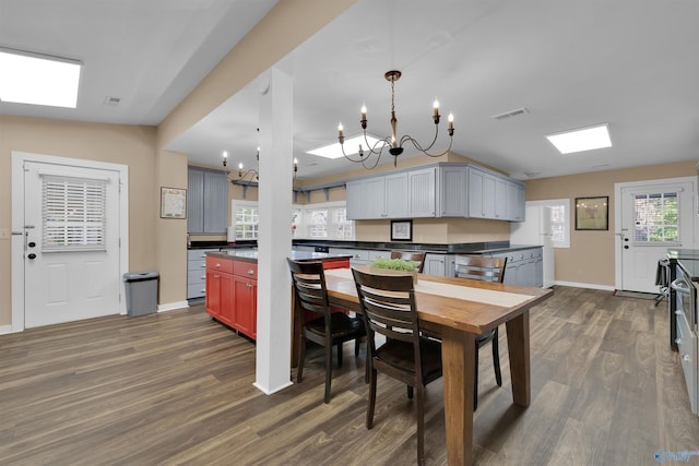 kitchen with dark countertops, visible vents, baseboards, dark wood finished floors, and a chandelier