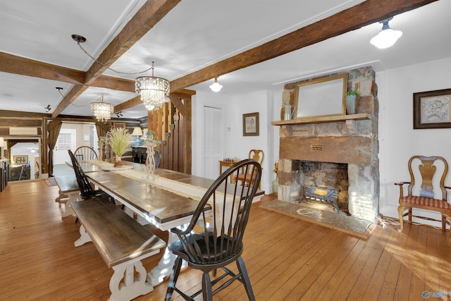 dining area featuring beamed ceiling, a fireplace, and hardwood / wood-style flooring