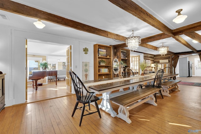 dining area featuring beam ceiling, light wood-style flooring, a notable chandelier, and visible vents