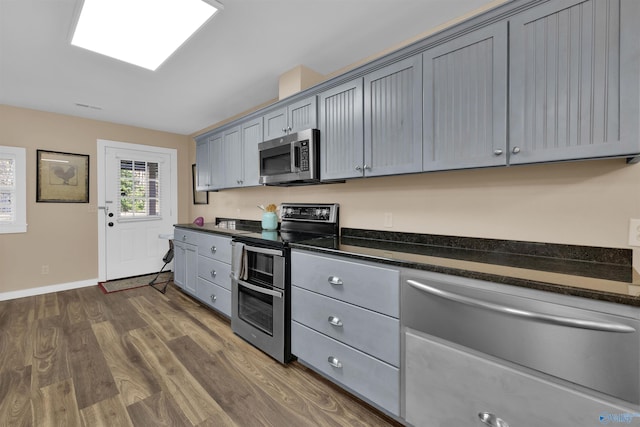 kitchen featuring visible vents, gray cabinets, dark wood-style floors, stainless steel appliances, and baseboards