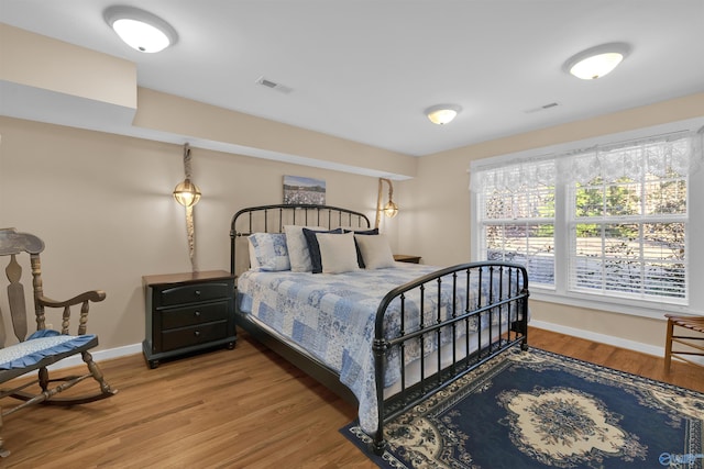 bedroom with wood finished floors, visible vents, and baseboards