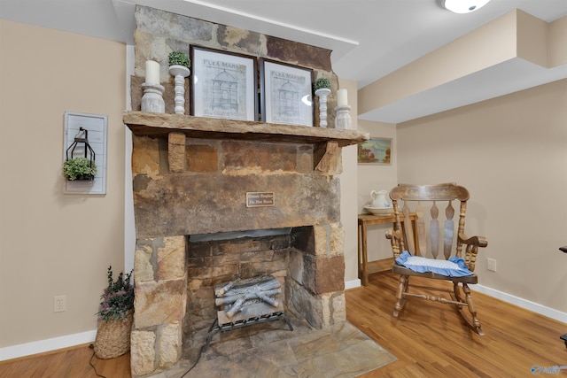 interior details featuring a stone fireplace, wood finished floors, and baseboards