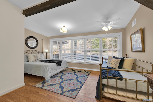 bedroom with hardwood / wood-style flooring, vaulted ceiling with beams, baseboards, and visible vents