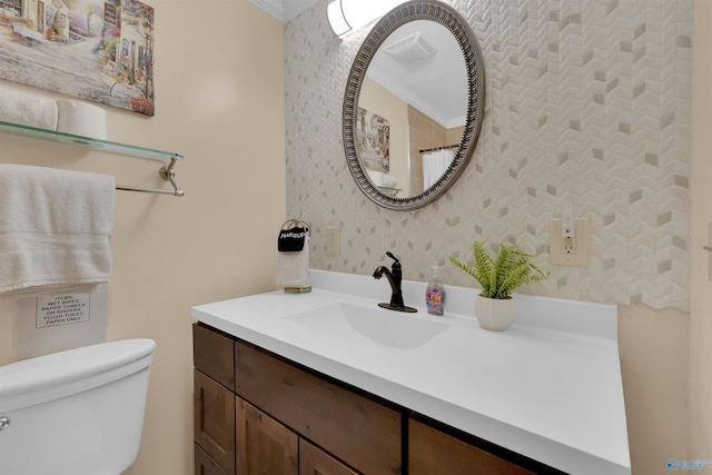 bathroom featuring toilet, wallpapered walls, vanity, and crown molding