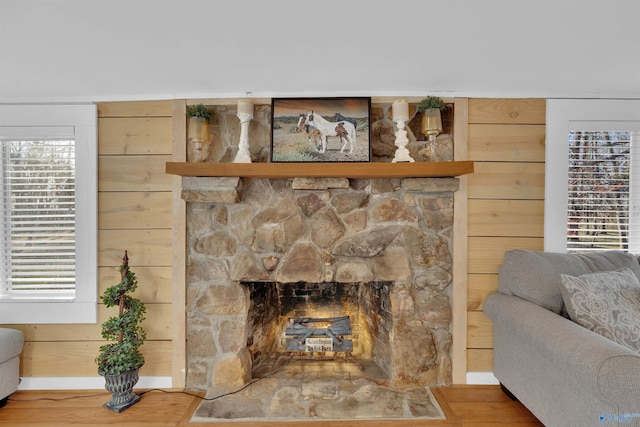 details featuring a stone fireplace, wood finished floors, and wood walls