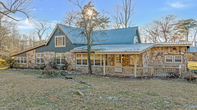 rear view of house with metal roof, stone siding, and covered porch