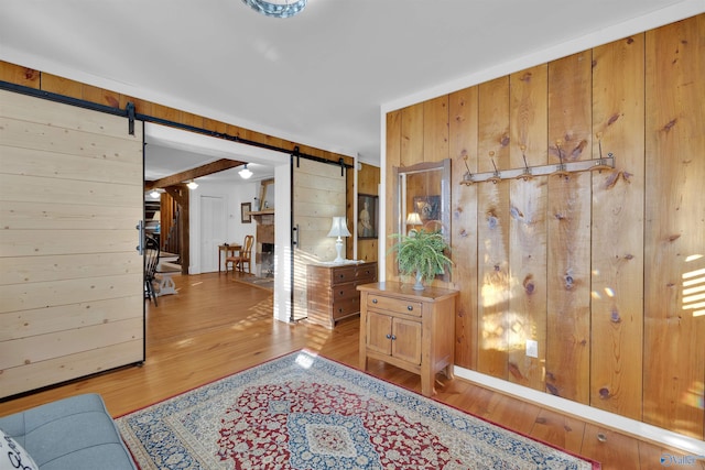 interior space with a barn door, wooden walls, and hardwood / wood-style flooring