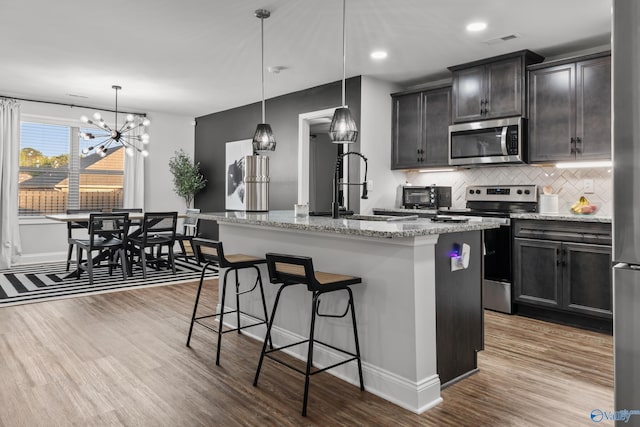 132 Fall Meadow Dr, Harvest, AL 35749 - kitchen featuring appliances with stainless steel finishes, a sink, wood finished floors, decorative backsplash, and a kitchen breakfast bar