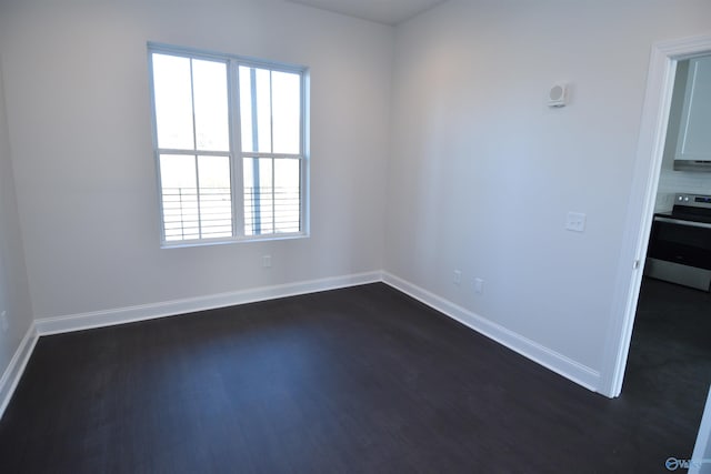 spare room with dark wood-style flooring and baseboards