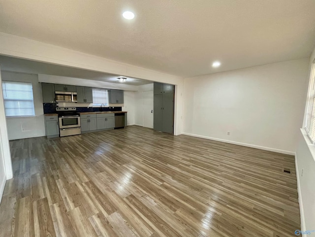 unfurnished living room featuring baseboards, visible vents, wood finished floors, a sink, and recessed lighting