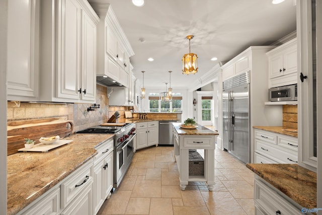 kitchen featuring white cabinetry, light stone counters, built in appliances, a notable chandelier, and pendant lighting