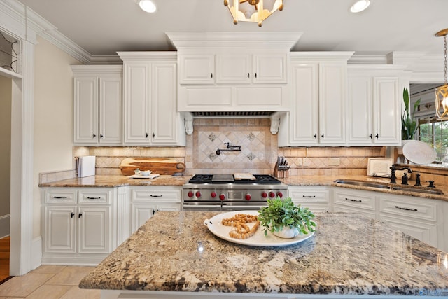 kitchen with sink, crown molding, light stone counters, white cabinets, and range with two ovens