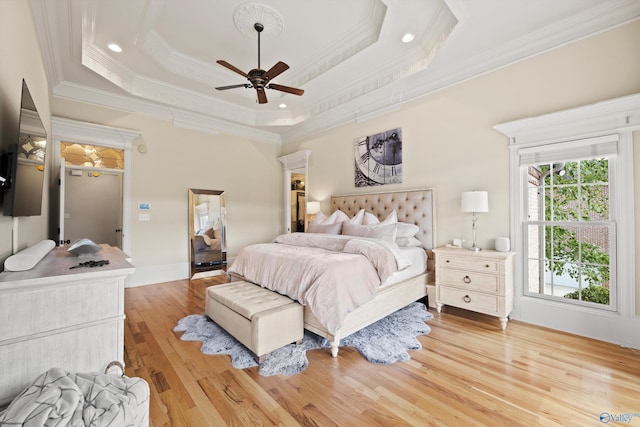 bedroom featuring a raised ceiling, ornamental molding, ceiling fan, and light hardwood / wood-style floors