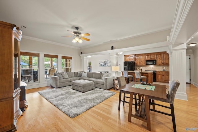 living room with decorative columns, ornamental molding, ceiling fan, and light hardwood / wood-style floors