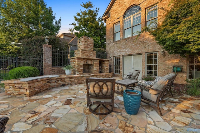 patio terrace at dusk with an outdoor stone fireplace