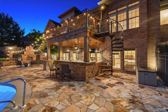 view of patio with ceiling fan, a balcony, a fireplace, and a bar