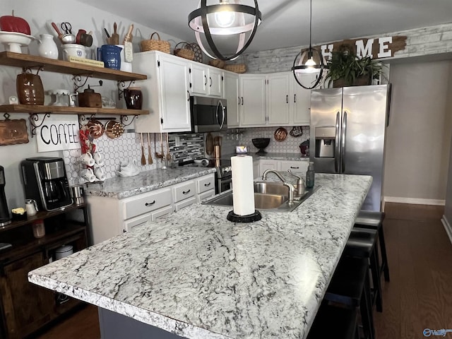 kitchen featuring tasteful backsplash, appliances with stainless steel finishes, a kitchen island with sink, white cabinetry, and a sink