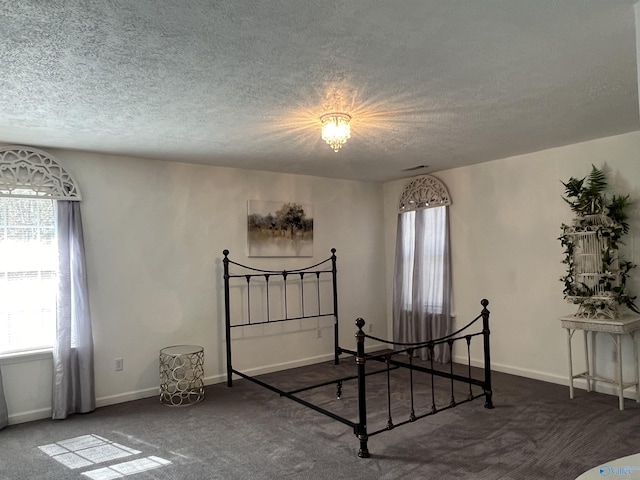 unfurnished bedroom with a textured ceiling, carpet floors, and baseboards