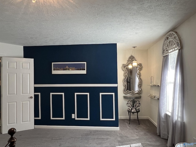 interior space featuring carpet floors, a textured ceiling, and baseboards