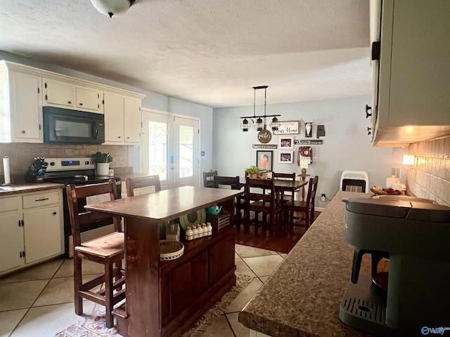 kitchen featuring pendant lighting, light tile patterned floors, tasteful backsplash, and stainless steel range with electric cooktop